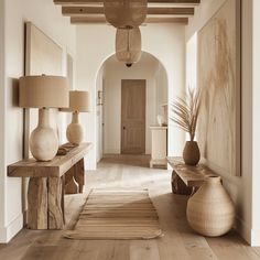 a hallway with two large vases on either side of the wall and a wooden bench in front of it