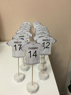 soccer jersey cupcake toppers are displayed on a white cake stand in front of a wall