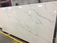 a large white marble slab is being displayed in a warehouse with yellow lines on the floor