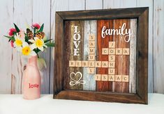 a vase with flowers sitting next to a scrabble tile frame that says love