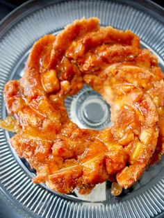 a bundt cake sitting on top of a glass plate covered in sauce and toppings