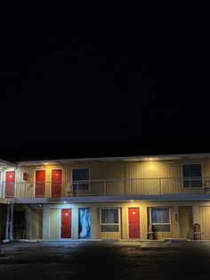 an apartment building lit up at night with red doors and windows on the second floor