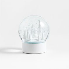 a snow globe with sailboats in it on a white surface and water droplets all around