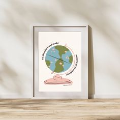 an art print with the earth on it in front of a white wall and wooden floor