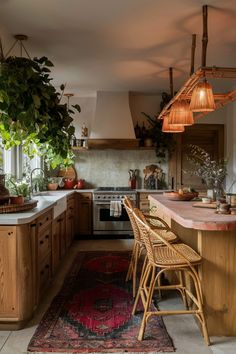 Rustic kitchen with wooden cabinets, hanging wicker lights, indoor plants, and a red patterned rug. Eco House Kitchen, Boho Midcentury Modern Kitchen, Boho Kitchen Aesthetic, Earthy Boho Kitchen, Bold Kitchen Design, Country Boho Kitchen, Hippie Interior Design, Modern Bohemian Kitchen