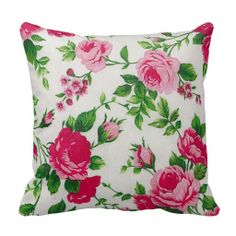 a white pillow with pink roses on it and green leaves around the edges is featured against a white background