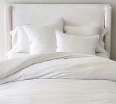 a bed with white sheets and pillows on it