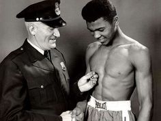 two men in uniforms standing next to each other and one is tying the mans belt