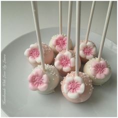 cake pops with pink and white frosting decorated with flowers on a plate, ready to be eaten