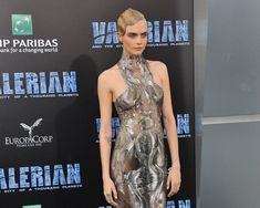 a woman in a silver dress standing on a red carpet