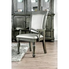 an elegant dining room chair with silver upholstered back and arm rests on a rug in front of a china cabinet