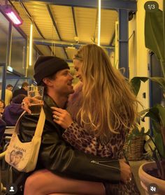 a man and woman sitting next to each other in front of a building with plants