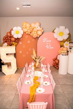 a table set up for a party with balloons and flowers