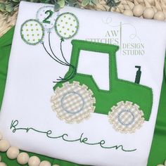 a green tractor with balloons on it is sitting next to some white balls and greenery