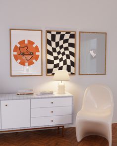 a white chair sitting next to a table with a lamp and pictures on the wall