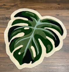 a large green leaf shaped rug on top of a wooden floor