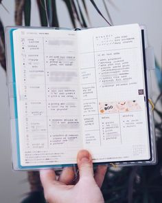 a person holding an open book in their left hand with writing on the pages and japanese characters