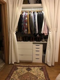 an open closet with clothes and shoes hanging on the rack, next to a rug