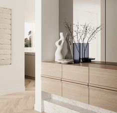 a white vase sitting on top of a wooden dresser next to a wall mounted mirror