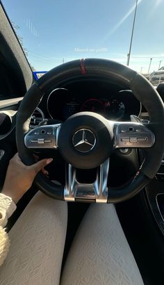 a woman is sitting in the driver's seat of a car with her hands on the steering wheel