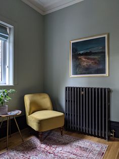 a yellow chair sitting in front of a radiator next to a table with a potted plant on it