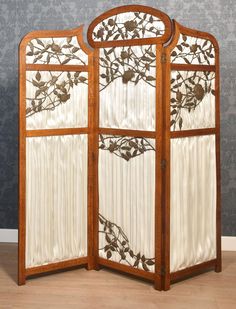 a room divider made out of wood and fabric with flowers on it, in front of a wallpapered background