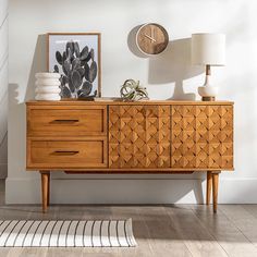 a wooden dresser sitting next to a white wall with a clock on top of it