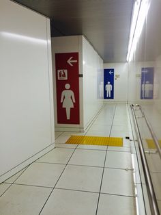 a white tiled floor with two red and blue signs on the wall next to each other