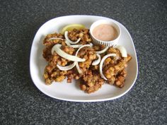 a white plate topped with fried food and dipping sauce