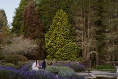 a bride and groom walking through the gardens