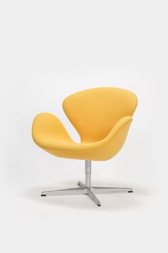 an egg chair with a metal base and yellow upholstered fabric