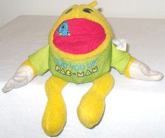 a yellow stuffed animal sitting on top of a white bed next to a wall with the words pac - man written on it