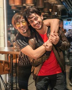 two young men hugging each other in front of a table