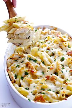 a white dish filled with macaroni and cheese being held by a tortilla chip