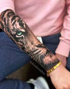 a person with a tiger tattoo on their arm and the other hand is holding something