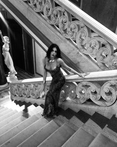 black and white photograph of a woman sitting on the stairs in front of a staircase