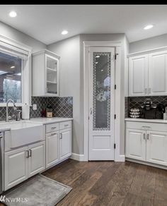 a kitchen with white cabinets and wood floors