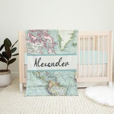 a baby crib with a world map and name blanket on it, next to a potted plant