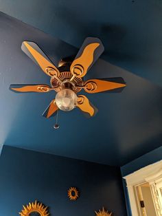 a ceiling fan in a blue room with sunflowers on the wall and other decorations