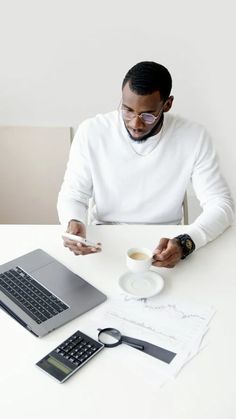 a man sitting at a table with a laptop and coffee