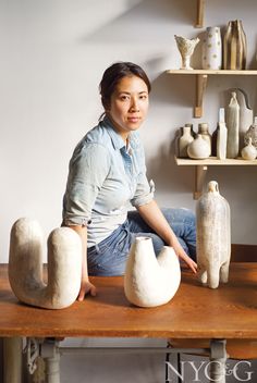 a woman sitting at a table with vases on it