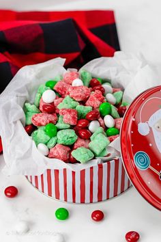 a red tin filled with christmas candy and marshmallows on top of it