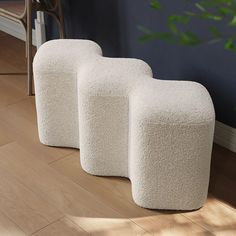 three white stools sitting on top of a hard wood floor next to a plant