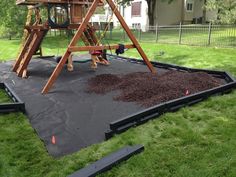 a wooden swing set in the middle of some grass