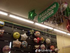 balloons are hanging from the ceiling in front of a green balloon center sign that reads balloon center