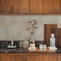 a kitchen counter topped with lots of bottles and vases next to each other on top of a wooden cabinet