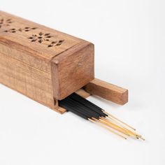 a wooden box with two black sticks sticking out of it's side and an intricate design on the lid