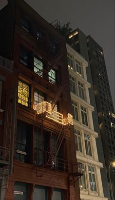 an apartment building is lit up at night with lights on the balconies and fire escapes