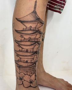 a person with a tattoo on their leg that has a pagoda in the middle and flowers at the bottom