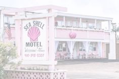 a pink motel sign sitting in front of a tall building with white windows and balconies